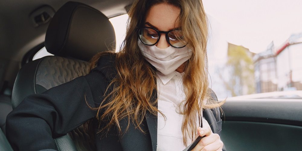 Businesswoman in a black mask sitting inside a car